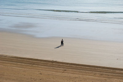 Two people walking on beach