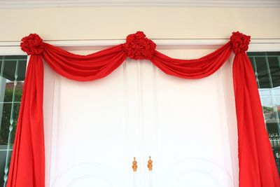 Low angle view of red flags hanging against curtain