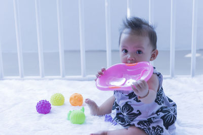 Portrait of cute baby girl playing with toy at home