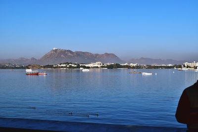 Sailboats moored on sea against clear blue sky