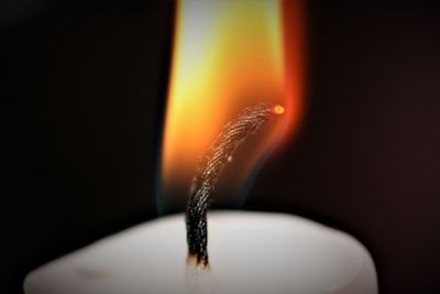 Close-up of lit candle against black background