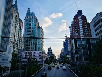 Cars on road amidst buildings in city against sky