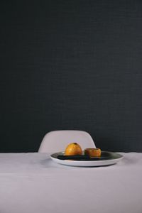 Oranges in plate on table against wall