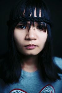 Portrait of young woman against black background