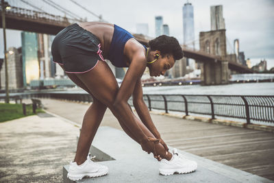 Woman exercising on bridge in city