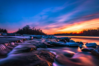 Surface level of lake against sky during sunset