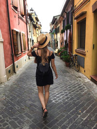 Woman walking on footpath amidst buildings in city