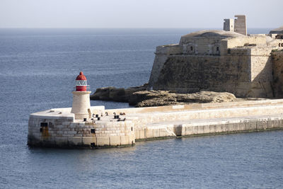 Lighthouse by sea against sky