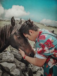 Side view of man touching horse on land