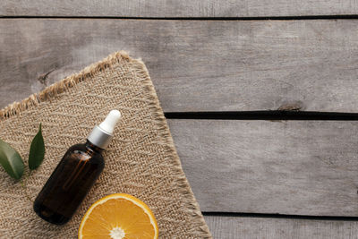 Orange essential oil in glass bottle with green leaf. cosmetic concept on wooden background