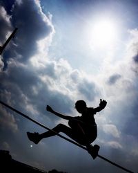 Low angle view of silhouette person playing against sky