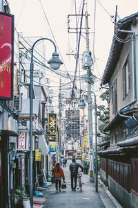 Rear view of people walking on street amidst buildings in city