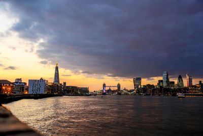 View of thames river amidst city against cloudy sky at dusk