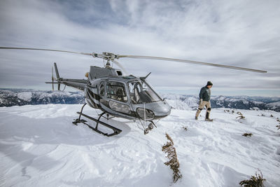 Helicopter pilot explores a snow-covered mountain summit.