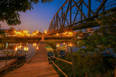 Railway bridge and footbridge over against sky at dusk