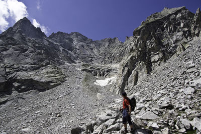 People on rocks by mountains against sky