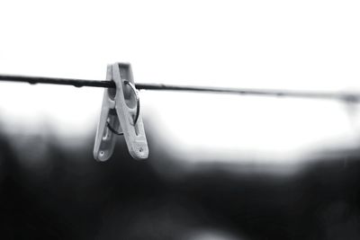 Close-up of clothespin on clothesline against clear sky