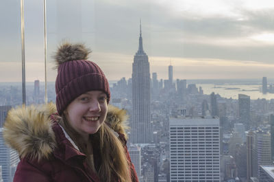 Portrait of smiling young woman standing on snow in city