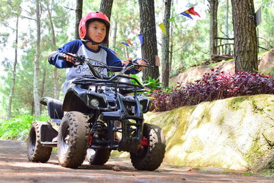 Full length of a boy riding motorcycle in forest