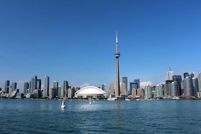 City at waterfront against blue sky