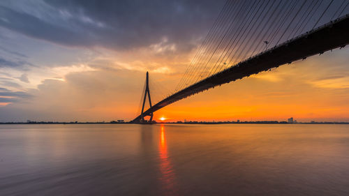 Bridge over sea against sky during sunset