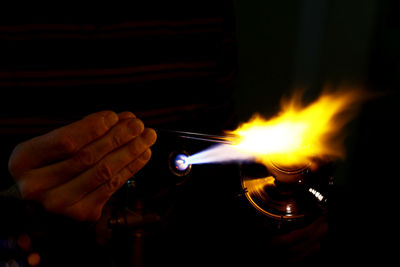 Close-up of hand heating metal in darkroom