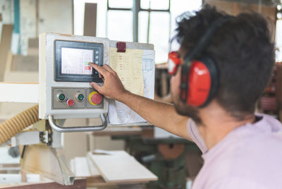 Male carpenter operating machine while working in workshop