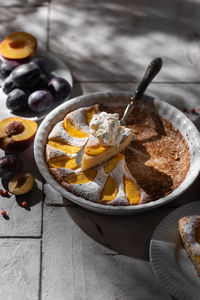 Selective focus home made nectarine pie with whipped cream on tile table with shadows from leaves