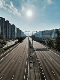 Vehicles on road against sky in city