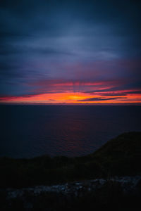 Scenic view of sea against dramatic sky during sunset