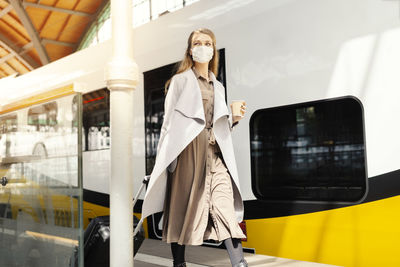 Woman wearing mask walking on railroad station