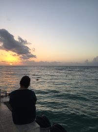 Rear view of man looking at sea against sky