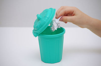 Close-up of hand holding bottle against white background