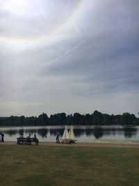 People sitting on golf course against sky