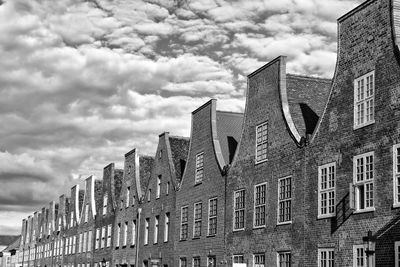 View of bricked houses in a row against cloudy sky