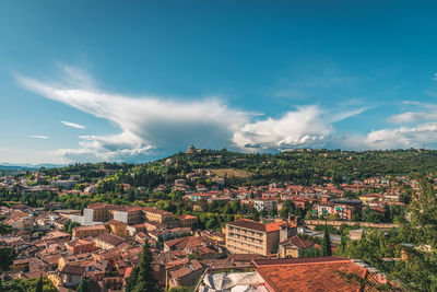 Aerial view of houses in town against blue sky