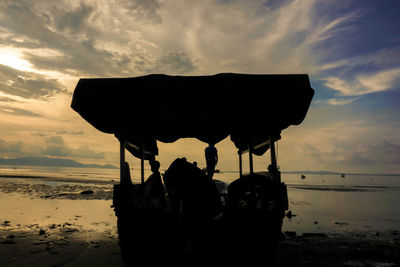 Silhouette people on beach against sky during sunset