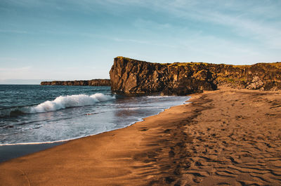 Rock formations on beach against sky