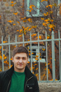 Portrait of young man with autumn leaves against trees