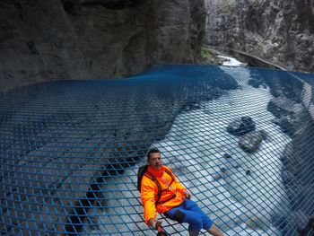 High angle portrait of mature man on net over river amidst rock formations