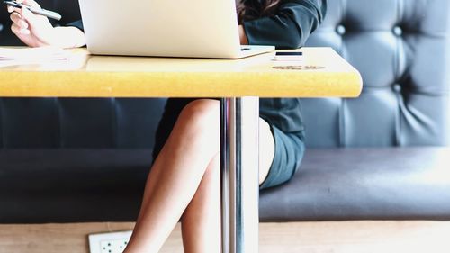 Midsection of woman using laptop at desk