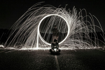 Full length of silhouette woman playing with light trails at night