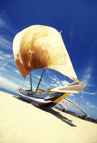 Outrigger boat moored at beach during sunny day