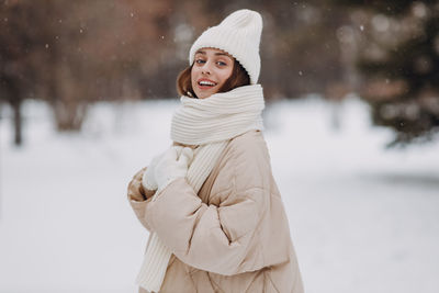Portrait of young woman standing against snow