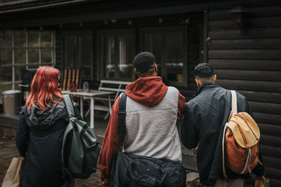 Rear view of friends walking towards cabin during vacation