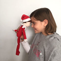 Cute girl holding red toy while standing against white wall