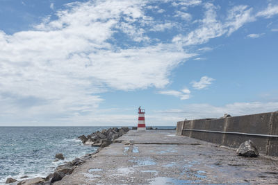 Lighthouse by sea against sky