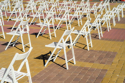 White folding chairs are placed on the square on pavement. quarantine restrictions