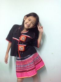 Smiling young woman standing against white wall