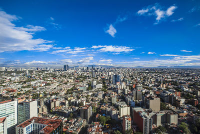 High angle view of modern buildings against blue sky